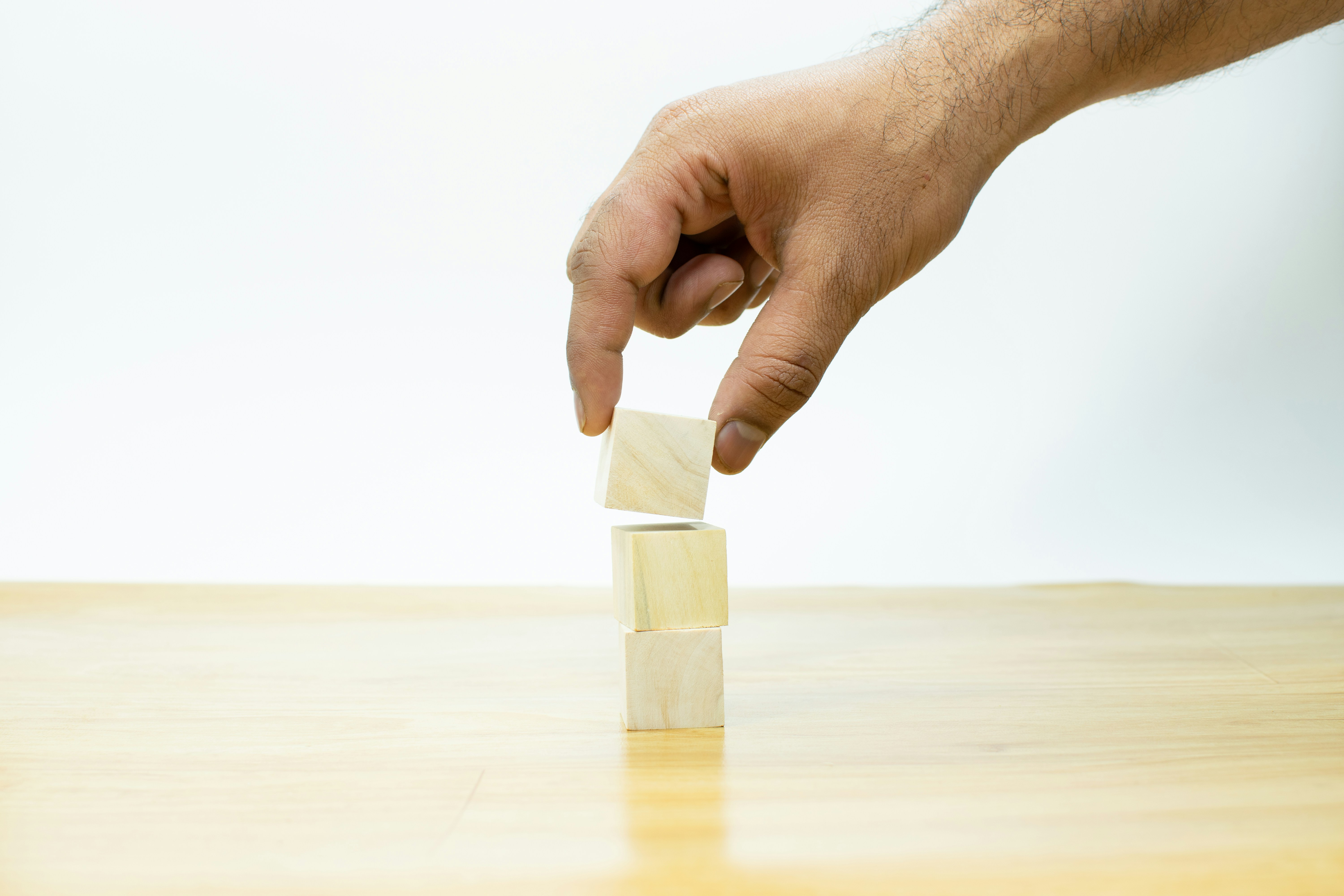 A hand stacking wooden cubes